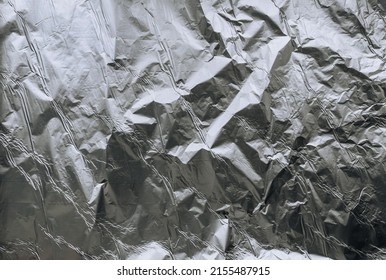 Background, Texture Of Silver Shiny Foil, Colored Crumpled Paper For Packing Goods. Close-up Photo, Top View, Copy Space, Abstraction.