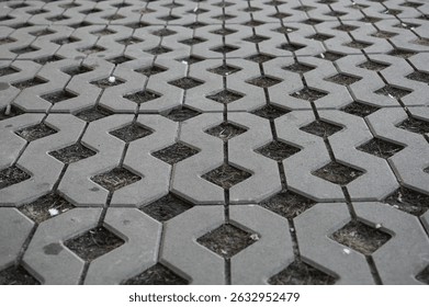 Background texture of square tiles made of gray natural stone. Concrete street covering of road, geometric paving pattern, green lawn and eco parking, green parking, sustainable development city