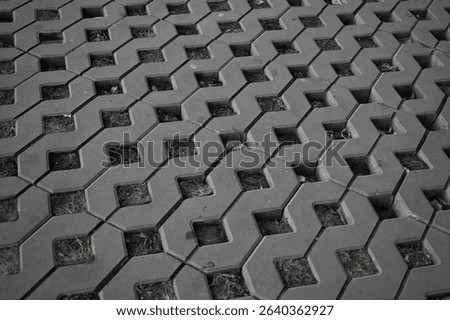 Background texture of square tiles made of gray natural stone. Concrete street covering of road, geometric paving pattern, green lawn and eco parking, green parking, sustainable development city