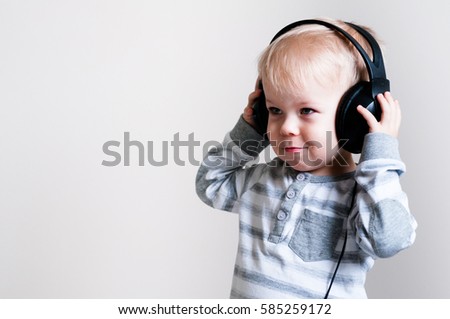 Background with twoyears old boy listens to music in headphones, holding in hands the phone and the handset.