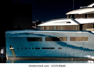Background urban photo of a modern luxurious super yacht anchored in a big city port at sunset