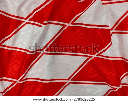 Background view of bold red and white geometric pattern reminiscent of classic 90s football jersey fabric, with a textured sporty look.