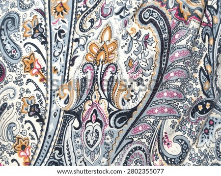 Background view of intricate paisley pattern fabric with vintage floral motifs, featuring fuchsia pink, mustard yellow, and navy blue details on an off-white textile background.