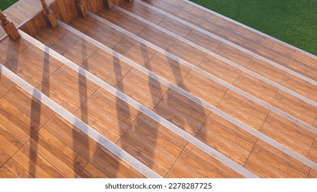 Background of Vintage Wooden Tile Steps and artificial grass Floor with sunlight and Railing Shadow on Surface, top view with copy space - Powered by Shutterstock