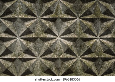 Background, wall of gray blocks with triangular patterns and shadows of the sun close up