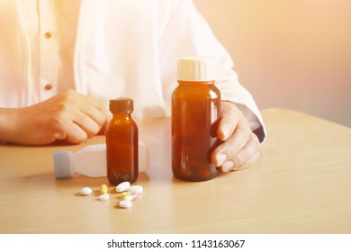 Background In Warm Light
Asian Man Doctor Holding A Bottle Of Pills On A Brown Table And Empty Space For Text.