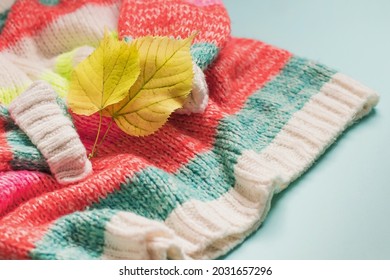 Background With A Warm Sweater. Knitted Clothes With Autumn Leaves, Bright Background, Knitwear, Place For Text, Autumn-winter Concept. Copy Space.