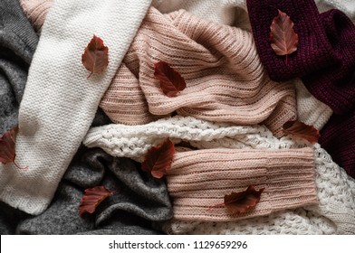 Background with warm sweaters. Pile of knitted clothes with autumn leaves, warm background, knitwear, space for text, Autumn winter concept. Copy Space. - Powered by Shutterstock