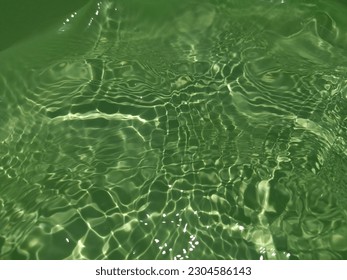 The​ metal​ texture​ of​ surface​ blue​ water​ reflected​ by​ sunlight​ for​ background. Blue​ water​ texture​ in​ deep​ sea​ for​ background. Reflection​ on​ surface​ blue​ water. Green​ wwater art.