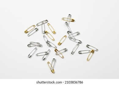Background of white color with little gold and silver safety pins scattered chaotically in center. Copy space. Mock up photography. Creative minimalism with office stationery. - Shutterstock ID 2103836786