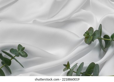 Background of white silk, stone and eucalyptus leaves