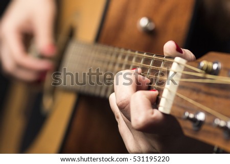 background Young woman clamped with fingers guitar strings and plays a melody
