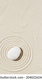 Background With Zen Stone On Sand. Zen Garden With Concentric Circles Around Pebble For Meditation And Tranquility. View From Above. Vertical Banner Mock Up For Social Media Stories.