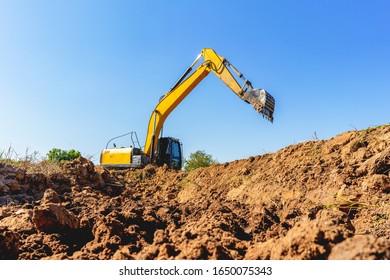 Backhoe Digging Up Soil To Prepare Agricultural Land. Excavator Is Digging A Hole To Find Water For Agriculture. Crawler Excavator Performs Earth Work.