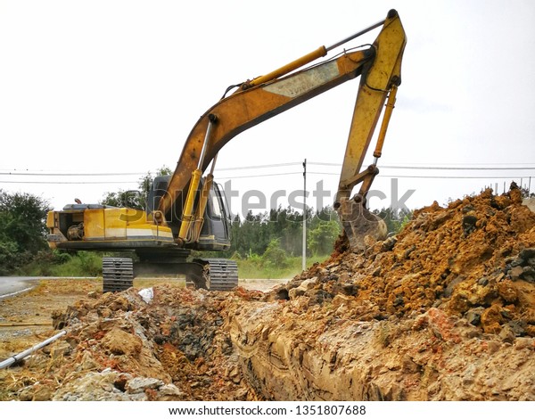 Backhoe to excavate the soil on the\
ground construction site excavator. Installed construction of\
concrete pipe of drainage system work on the side of the road\
