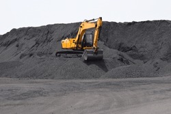 A Backhoe - Excavating Equipment, Digger Working On The Bulk Mountain Of Coal Imported At Dindayal Port Trust, Kandla. Gujarat - India