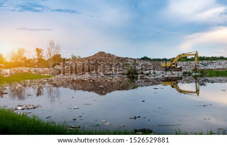 Backhoe is lifting refuse at waste separation plant, Mountain large garbage pile and pollution, Pile of stink and toxic residue