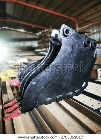 Backhoe loader digging bucket positioned at a construction site. Heavy-duty attachment used for excavation, earthmoving, and general construction work.