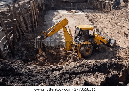 Backhoe loader digging the ground for building infrastructure and foundations.