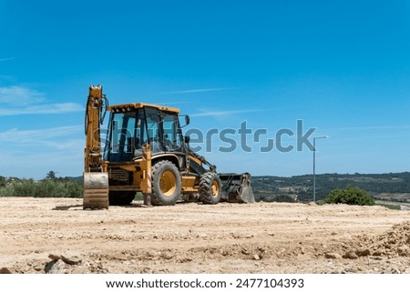 Backhoe loader in operation for leveling soil for construction of lots
