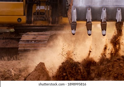 Backhoe working by digging soil at construction site. Bucket teeth of backhoe digging soil. Crawler excavator digging on soil. Excavating machine. Earth moving machine. Excavation vehicle.