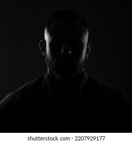 Backlight portrait hidden face in the shadow, male person silhouette on dark background