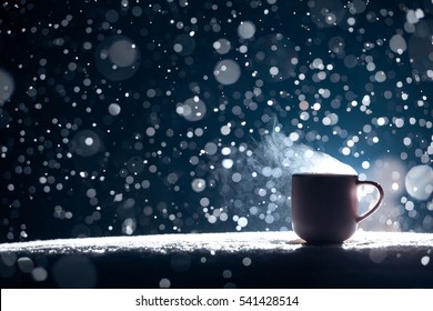 Backlighted Cup Of Hot Coffee On Night Snowy Background; Mug With Warm Tea In Snow Winter Weather;