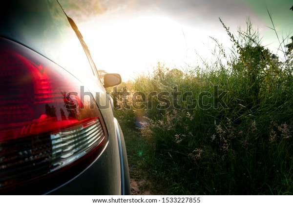 Backlighting image of a car rear light reservation\
with a bright morning green\
meadow