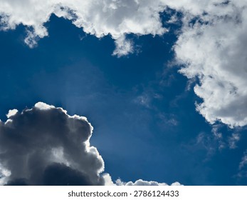 Backlit clouds frame a deep blue sky. Sunlight glows through a dramatic cloudscape. Weather background for nature and atmosphere.