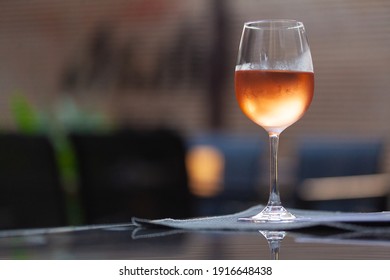 Backlit Glass Of Cold Rose Wine Sitting On The Table