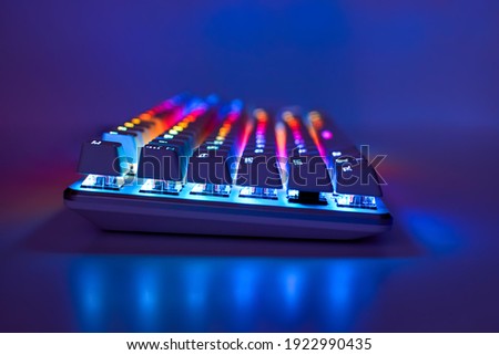 Backlit keyboard. Gaming keyboard with RGB light, side view. Colorful keyboard in neon light, soft focus