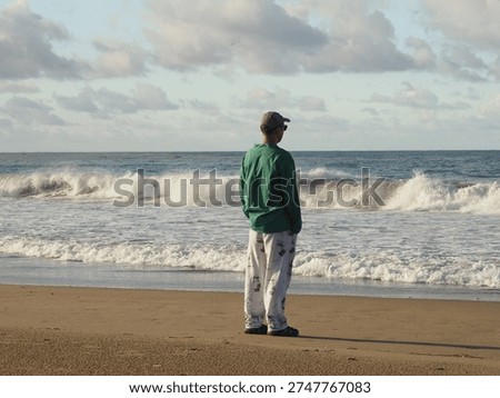 Backlit man in cap and sunglasses facing the sea, Indonesian coast