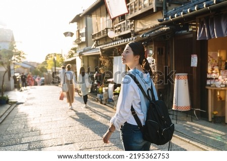 backlit photograph asian female backpacker is gazing into the distance with curiosity while walking down historic ninen zaka street at dusk in autumn Kyoto japan