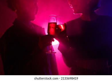 Backlit Portrait Of Two Young Women Enjoying Drink While Partying In Smoky Club With Neon Lights, Copy Space