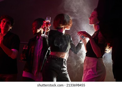 Backlit Portrait Of Two Young Women Dancing In Crowd While Partying In Smoky Club, Copy Space