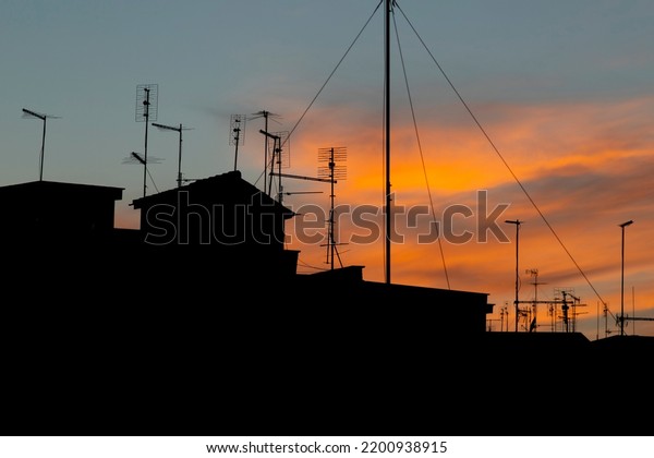 Backlit profile of buildings and television\
antennas, huge full moon in the\
sky.