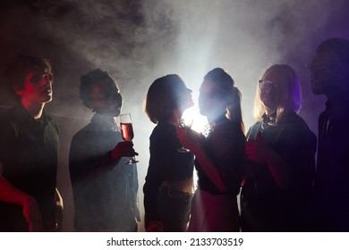 Backlit Shot Of Young People Dancing At Party, Silhouettes In Smoky Club