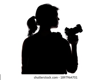 Backlit silhouette of a female photographer hiking and isolated on a white background for composites.  She is holding a camera and posing as a journalist or a hobbyist
