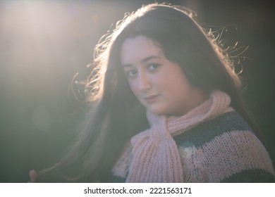 Backlit View Of Young Girl Touching Hair.