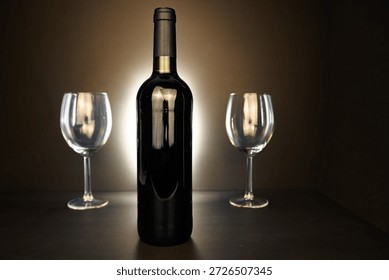 Backlit wine bottle and two empty glasses on a dark background, elegant studio still life with copy space.