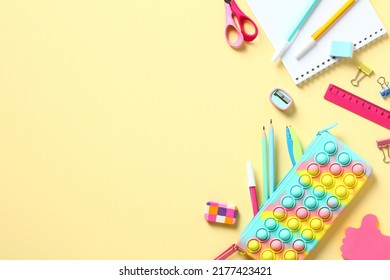 Backpack with colorful school supplies and digital table on yellow background, top view. Back to school concept. Flat lay.