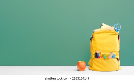 Backpack with different colorful stationery and apple on table and green background. Banner design back to school concept background. - Powered by Shutterstock