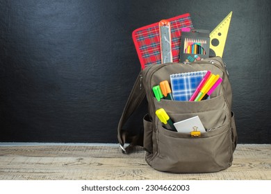 Backpack with different colorful stationery on table. Black background. Back to school - Shutterstock ID 2304662003