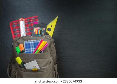 Backpack with different colorful stationery on table. Black background. Back to school - Shutterstock ID 2385074933