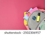 Backpack with different school supplies on pink background, top view. Space for text