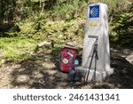 Backpack and other gear of a pilgrim to Santiago de Compostela leaning against a Camino de Santiago sign milestone