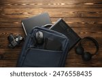 Backpack with photographer equipment and gadgets for work on a wooden background. Flat lay. Top view