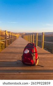 Backpack with pilgrim scallop shell (symbol of Camino de Santiago) on a wooden boardwalk. Pilgrimage concept. Way of St James, Camino de Santiago