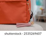 Backpack with pink leather keychain on soft surface indoors, closeup