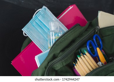 Backpack Prepared With Study Supplies And Mask For The Return To School. Covid-19 Concept.